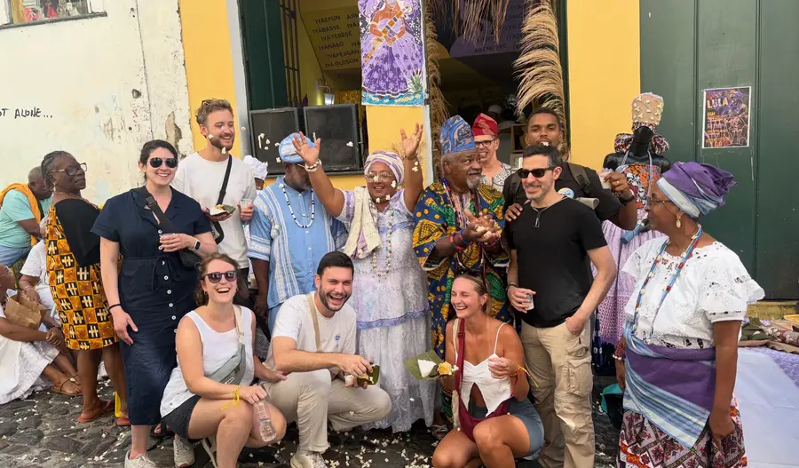 Travelers celebrating with baianas in traditional dress in Salvador